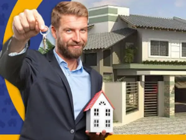 Corretor segurando a chave e uma casa em miniatura, com um sobrado ao fundo
