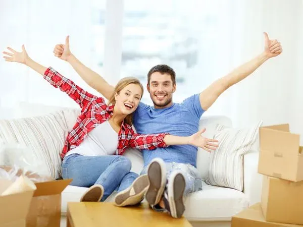 Casal comemorando no sofá entre caixas de mudança