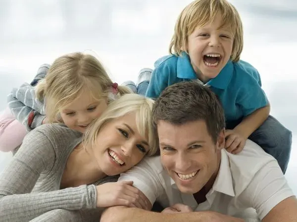 Família com duas crianças deitada no chão, rindo