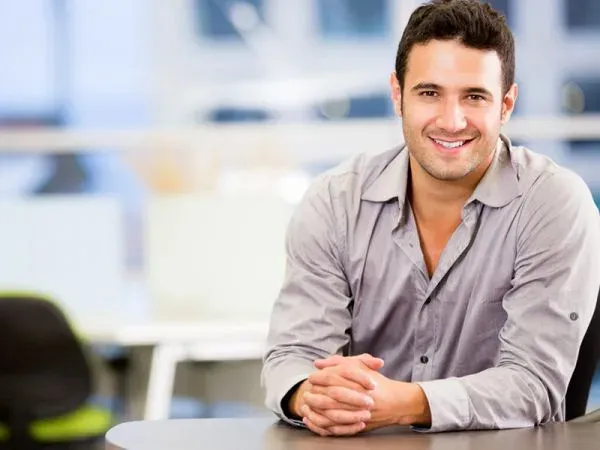 Homem de camisa social sentado à mesa de um escritório